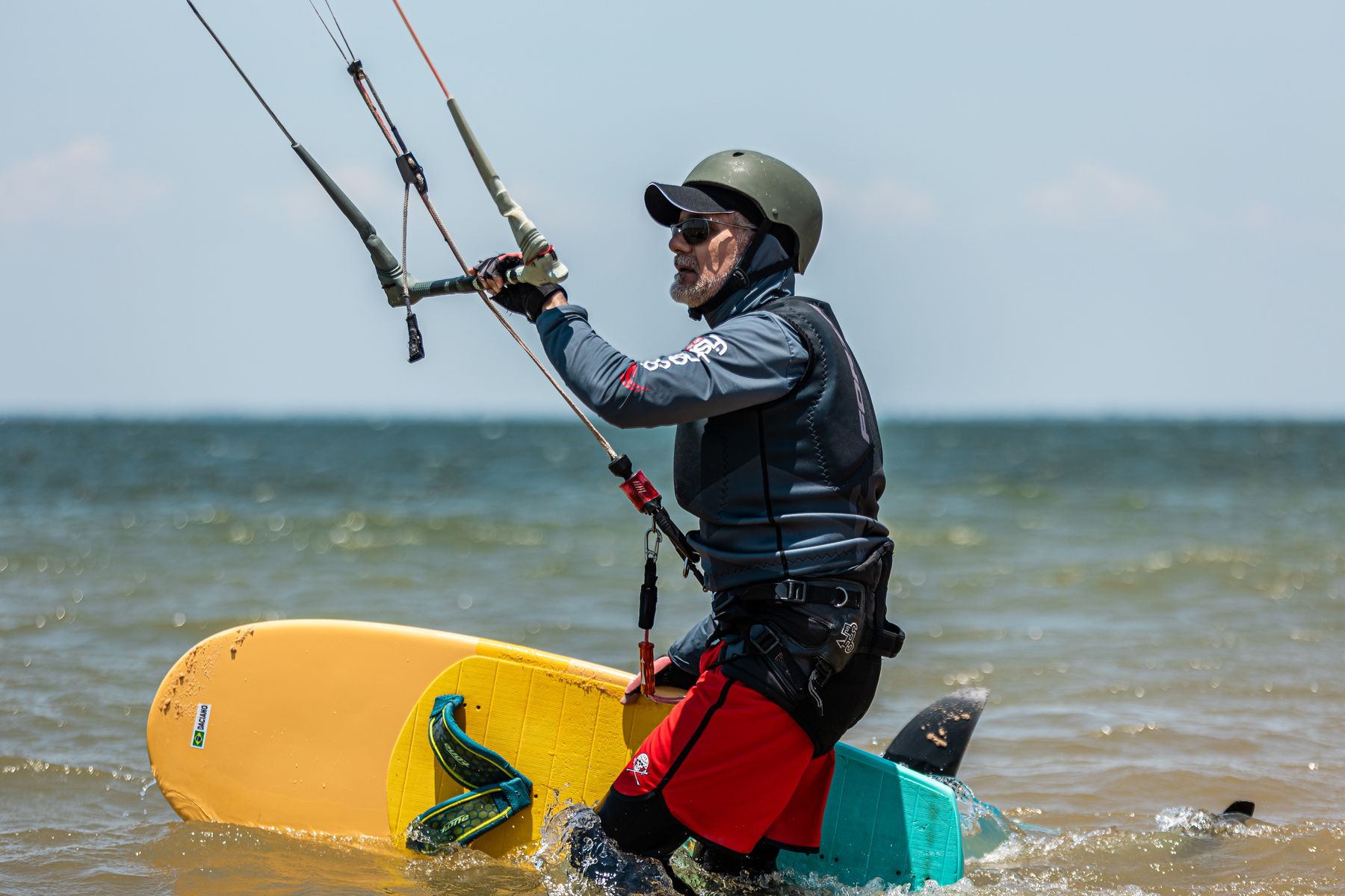 Kitesurfista de capacete com a prancha amarela